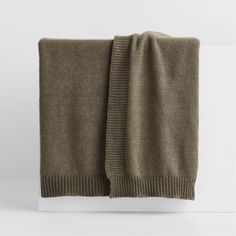 a brown sweater folded on top of a white surface