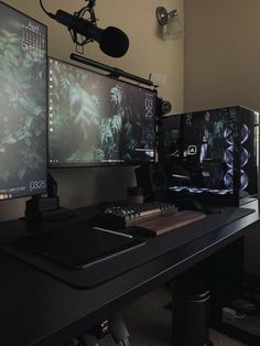 three computer monitors sitting on top of a desk next to a microphone and headphones