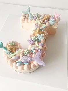 there is a cake shaped like the letter s with mermaids and seashells on it