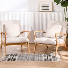 two chairs sitting next to each other on top of a hard wood floor in front of a white wall