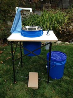 an outdoor table with two buckets and a blue towel on it in the grass