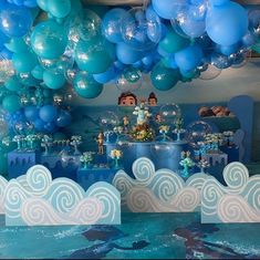 an ocean themed birthday party with blue and white balloons hanging from the ceiling above it