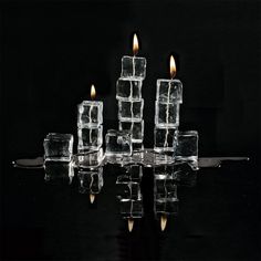 several ice cubes sitting on top of a table with one candle burning in the middle