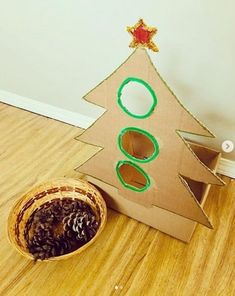 a cardboard christmas tree sitting on the floor next to a basket