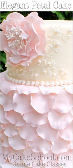 a three tiered cake with pink flowers on top and white icing, is shown