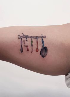 a person with a tattoo on their arm that has spoons and spatulas hanging from it