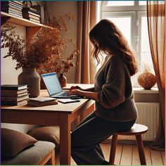 a woman sitting at a table with a laptop computer in front of her, looking out the window