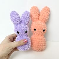 two small crocheted stuffed animals are being held by a person's hand