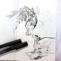 a drawing of a dragon and a bird on top of a piece of paper next to two markers