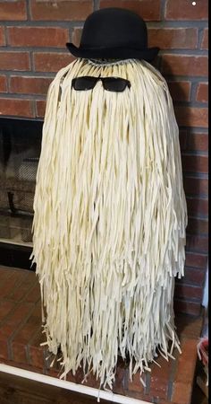 a hat and glasses on top of a fake long haired man in front of a fire place