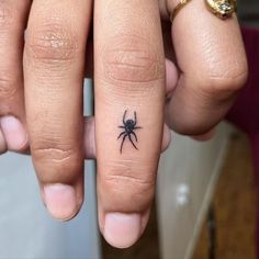 a person with a spider tattoo on their finger