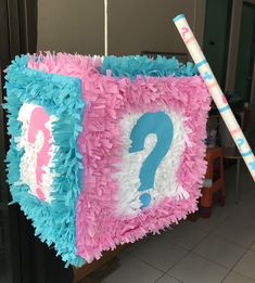 a pink, blue and white square with a question mark on it hanging from a line