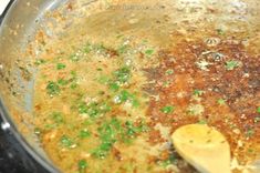 the food is being cooked in the pan on the stove top with a wooden spoon