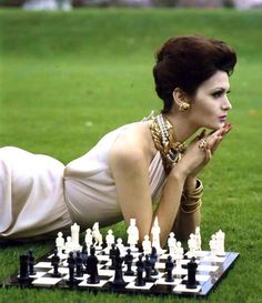 a woman laying on the ground next to a chess board