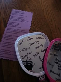 an open pink and white case with writing on it next to a purple piece of paper