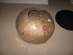 a paper mache ball sitting on the floor next to a black object with a red target painted on it