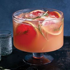 a drink in a glass with grapefruit, orange and rosemary garnish