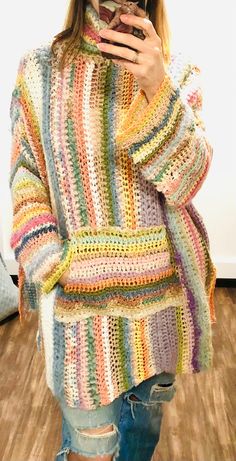 a woman taking a selfie while wearing a multicolored crochet sweater