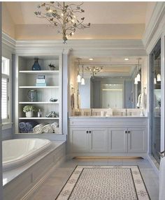 a bathroom with a tub, sink and large mirror