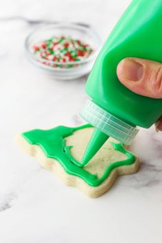 someone is decorating cookies with green icing