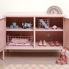 a pink shelf with baskets and toys on it in a child's playroom