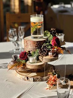 a table topped with a cake covered in pine cones and flowers next to wine glasses