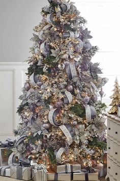 a decorated christmas tree with silver and gold ornaments on the top is surrounded by presents