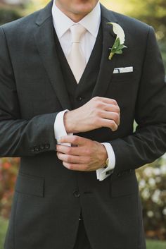 a man in a suit and tie with his hands on his lapel