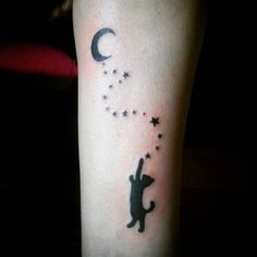 a cat with stars and a crescent tattoo on the left arm is shown in black ink