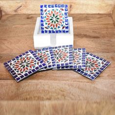 three pieces of colorful tile sitting on top of a wooden table