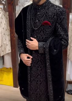 a man wearing a black and red sherwa in front of a rack of clothes