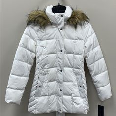 You'll Be So Bundled Up (And Chic) In This Ultra-Warm Puffer Coat By Tommy Hilfiger. Styled In That Perfect In-Between Length, It's Finished With A Luxe & Cozy Faux-Fur Trim. Funnel-Neck Collar With Removable Hood And Attached Faux-Fur Trim; Front Zipper Closure With Button Overlay Imported Lined Silver-Tone Hardware Snap Side Pockets Water Resistant Size & Fit Approx. Length: 29" From Center Back To Hem Winter White Outerwear With Double-lined Hood For Cold Weather, Winter White Outerwear With Double-lined Hood, Hooded Winter White Outerwear With Faux Fur Lining, Fitted White Hooded Winter Jacket, Fitted White Hooded Jacket For Winter, White Fitted Hooded Jacket For Winter, Fitted Hooded Outerwear With Faux Fur Lining, Fitted White Hooded Jacket For Fall, White Parka With Adjustable Hood For Cold Weather