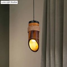 a light that is hanging from the ceiling in front of some curtained windows with curtains behind it