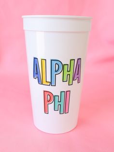 a white cup with the words alphabet phi on it sitting on a pink tablecloth