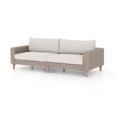 an outdoor sofa with white cushions and wooden legs, in front of a white background