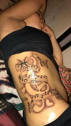 a woman's stomach with music notes and hearts tattoo on her side ribcage