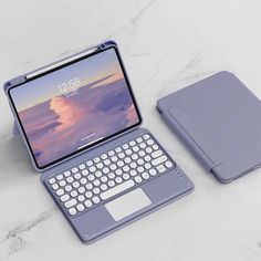 an open laptop computer sitting on top of a white marble counter next to a keyboard