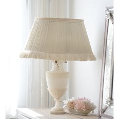 a white lamp sitting on top of a wooden table next to a mirror and vase