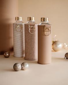 three bottles are sitting next to each other on a table with ornaments around them and one bottle is empty