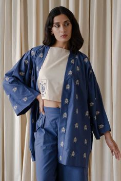 Blue full kimono sleeves shrug in organic cotton base with floral motif embroidery. Paired with sleeveless top and relaxed pleated and two patch pockets detail rayne pant.
Components: 3
Pattern: Patch Embroidery
Type Of Work: Bloom
Neckline: Top: Boat, Shrug: Open
Sleeve Type: Top: Sleeveless, Shrug: Kimono
Fabric: Organic Cotton
Color: Beige, Blue
Other Details: 
Attached inner lining
Length(in inches):
Top: 16.5
Rayne pant: 38
Model Height: 5ft 8inches, wearing size S
Occasion: Work - Aza Fash Cotton Sets With Kimono Sleeves For Summer, Summer Cotton Sets With Kimono Sleeves, Spring Cotton Kimono With Floral Embroidery, Spring Cotton Sets With Embroidered Sleeves, Embroidered Cotton Outerwear With Kimono Sleeves, Long Sleeve Cotton Shrug, Festive Cotton Top With Embroidered Sleeves, Casual Cotton Kimono With Floral Embroidery, Embroidered Cotton Sets For Loungewear