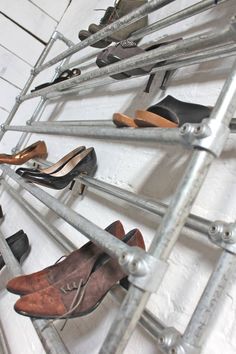 several pairs of shoes are lined up on a metal rack in front of a white brick wall