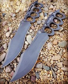 two knives are laying on the ground next to rocks