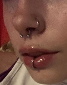 a close up of a person with piercings on their nose