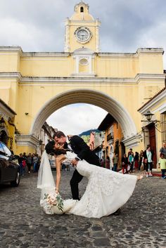 a bride and groom kissing in front of an archway