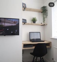 a laptop computer sitting on top of a wooden desk next to a wall mounted tv