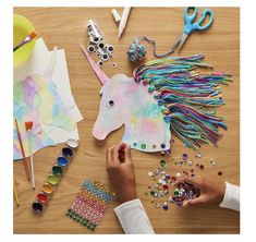 someone is making a unicorn mask out of paper and crafting it with colored beads