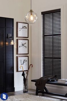 a living room with black shutters and pictures on the wall, umbrella stand in front of it