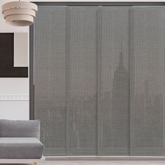 a couch sitting in front of a window covered in gray blinds and curtains over the windows