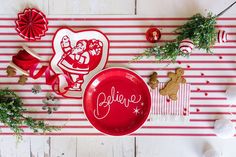 a red plate sitting on top of a table next to christmas decorations and other items