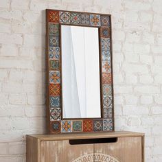 a mirror sitting on top of a wooden cabinet next to a brick wall and floor